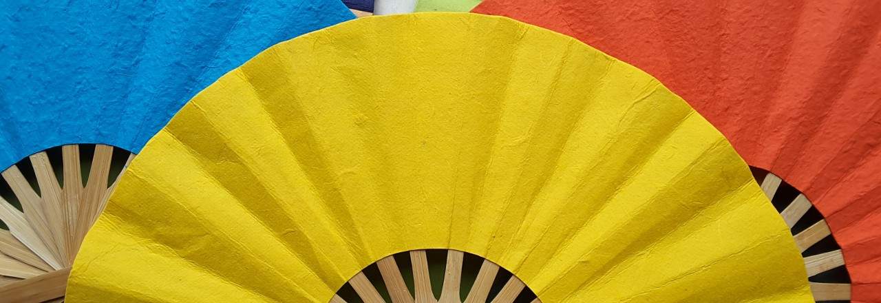 Three paper wedding fans in solid yellow, blue, red