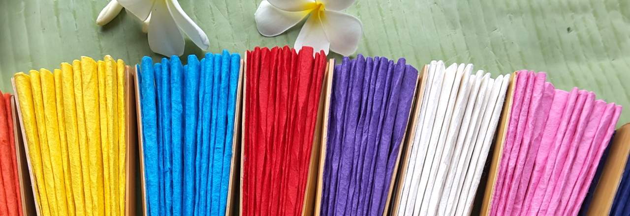 Folded solid color paper wedding fans garnished with Plumeria flowers