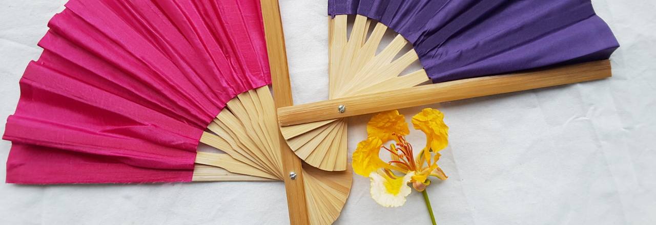 Two, half open, solid color silky fabric wedding fans in pink and violet