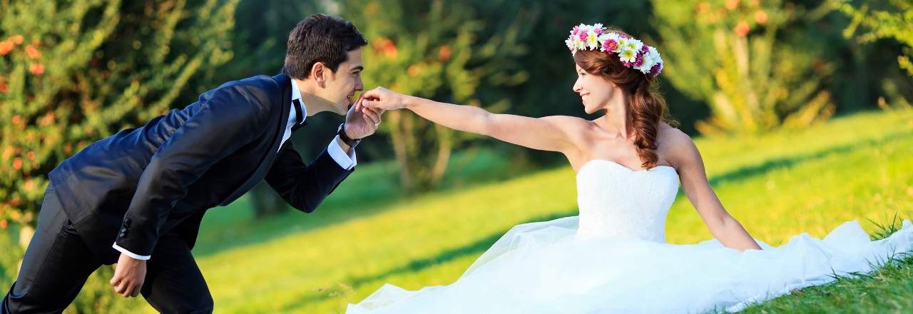 Bride and groom handkiss on the meadow